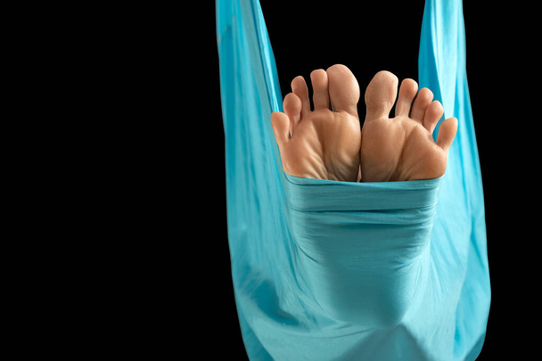 Close up bare feet in blue fabric hammock close-up on black background. Feet. Aerial gymnastics - Foto, Bild