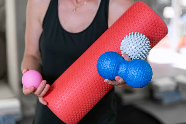 Young athletic woman holds equipment for MFR. Myofascial massage trainer. Different types myofascial rolls. Close up. - Foto, imagen