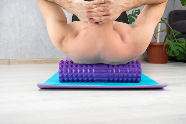 Чоловік робить масаж спини з міофасциальним роликом крупним планом. Тренування вдома. Міофасциальні м'язи спини. МФР
 - Фото, зображення