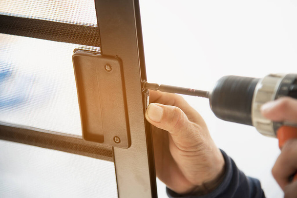 Man doing aluminum frame with glasses and wire screen door and window installation work in construction site - Valokuva, kuva