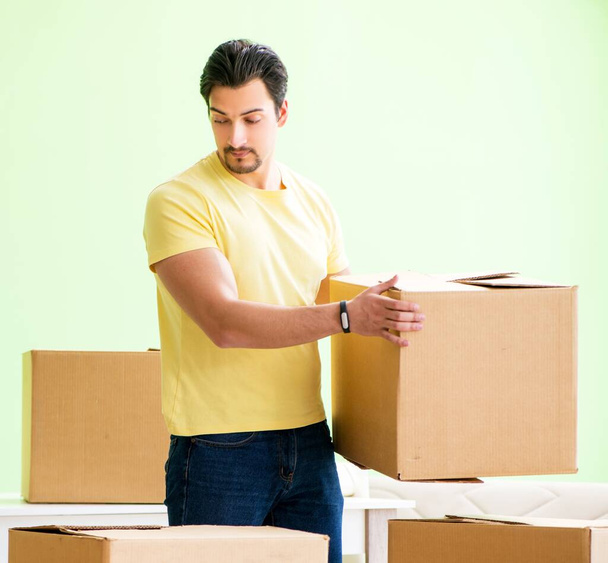 Young handsome man moving in to new house with boxes - Foto, Imagen