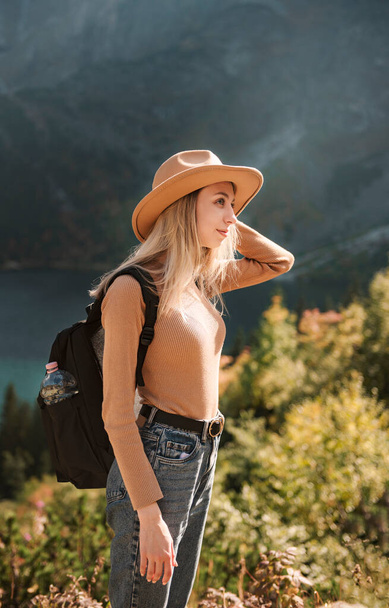 Женщина путешественник в шляпе и глядя на удивительные горы и озеро, странствий концепции путешествия. Морской глаз в польских Татрах. - Фото, изображение