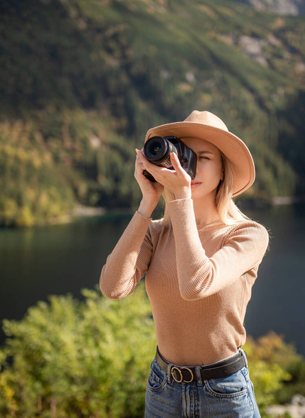 Подорожуючий фотограф стоїть на зеленій вершині гори, тримаючи в руках цифрову фотокамеру. Мандрівниця фотографує, дівчина насолоджується пейзажем природи в подорожі, відпочиває і святкує концепцію - Фото, зображення