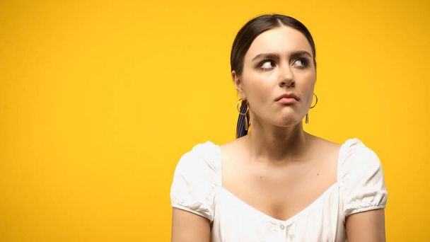 Sad woman in white blouse looking away isolated on yellow  - Foto, immagini