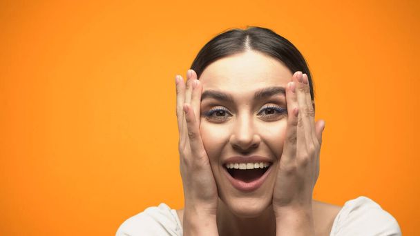 Cheerful woman looking at camera isolated on orange  - Photo, Image