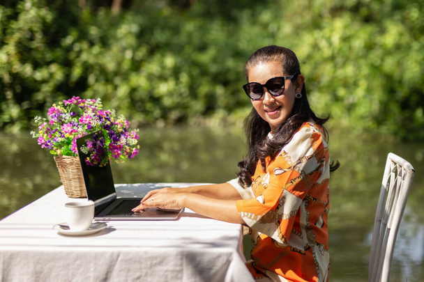 Porträt einer glücklich lächelnden Geschäftsfrau, die im Freien am Laptop arbeitet. - Foto, Bild