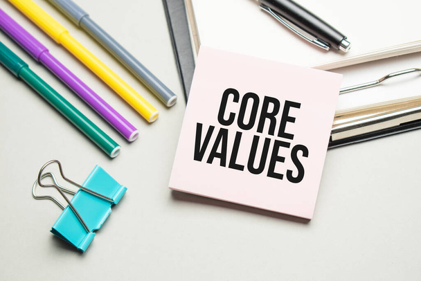 Reports and color charts are on the table. There are also red pens, pencil and paper in a black frame with the words Core Values - Foto, imagen