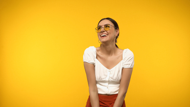 Happy woman in sunglasses and blouse looking up isolated on yellow  - Foto, Imagem