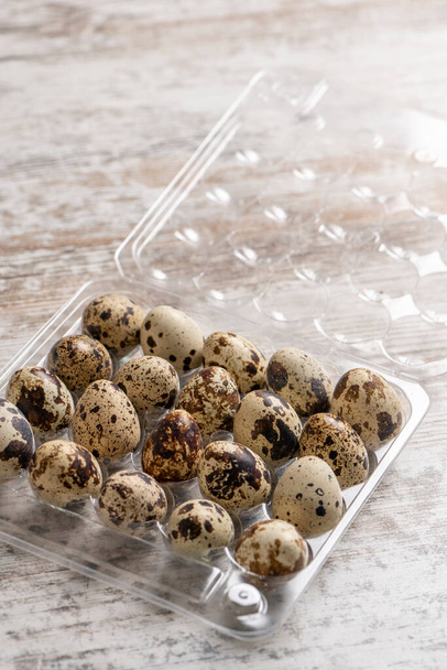 Quail eggs in plastic containers on a wooden table - Foto, afbeelding