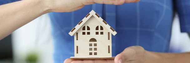 Female insurance agent is holding wooden house - Photo, Image