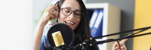 Young beautiful woman singing into microphone with headphones - Fotografie, Obrázek