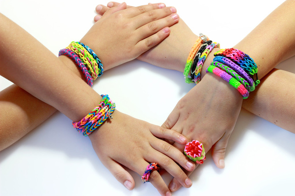 4 mão da menina com elástico e colorido arco-íris tear pulseira nas mãos
 - Foto, Imagem
