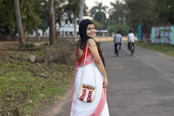 Kaunis intialainen nainen punaisessa saree ja pitkät hiukset poseeraa kameran tiellä - Valokuva, kuva