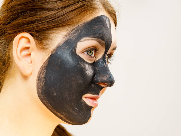 Skin care. Woman with charcoal facial mask, deep cleanser on face. Beauty, spa and acne treatment. Side view - Fotó, kép