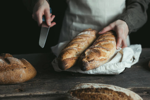 ライパンだ。女性の手がパンを切ろうとしてる。酵母のないパン。健康食品や伝統的なベーキングの概念。高品質の写真 - 写真・画像