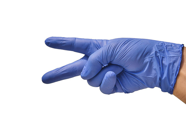 A doctor with a blue glove, puts his fingers in the shape of scissors, indicating a cut, while explaining how the surgery will be performed. - Zdjęcie, obraz