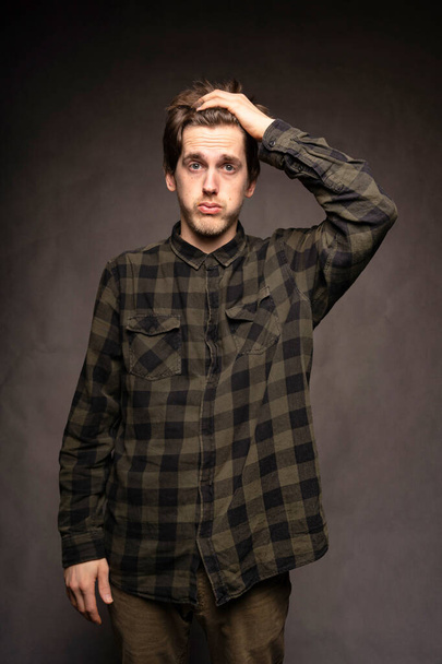 Young handsome tall slim white man with brown hair looking frustrated with flannel shirt on grey background - Foto, afbeelding