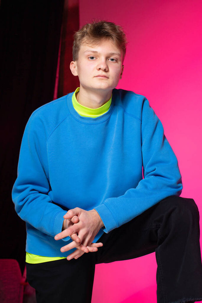 Young european boy with white skin in blue on pink black background - Фото, изображение