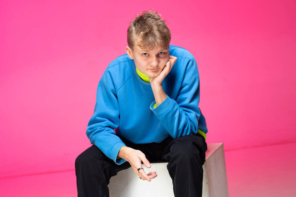 Young european boy with white skin isolated on pink in blue hoody - Foto, afbeelding