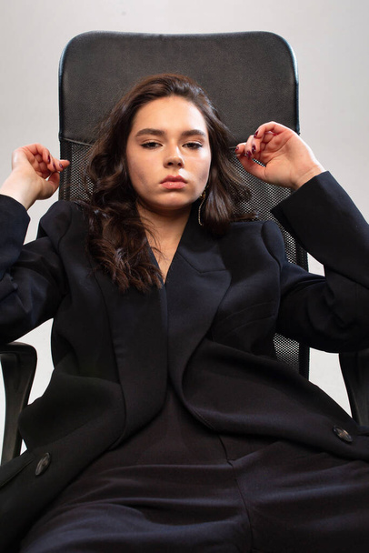 Dark long hair young european girl with white skin in office chair - Fotó, kép