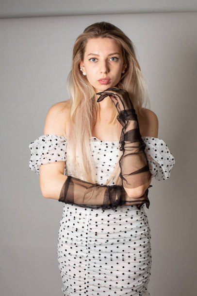 Young woman with blond hair and white skin isolated on dark grey in polka dot dress - Foto, Imagen