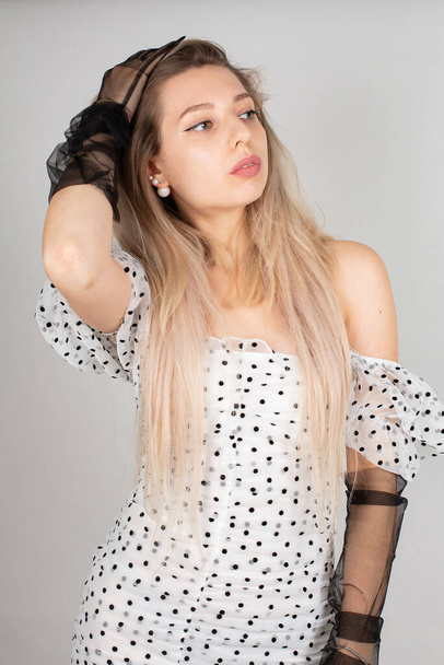 Romantic young woman with blond hair and white skin isolated on grey in white dress in dots - Foto, Imagem