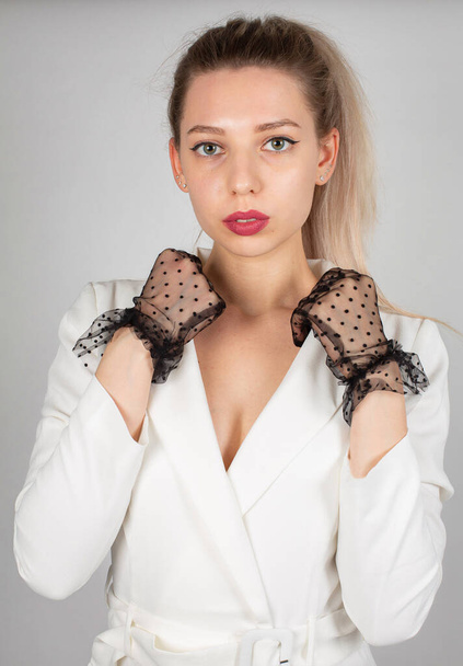 Portrait of woman with long hair and white skin isolated on grey in white dress with black lace gloves - Foto, Imagem