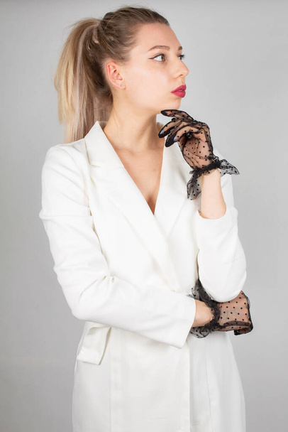 Woman with long hair and white skin isolated on grey in white dress with black lace gloves - Foto, imagen