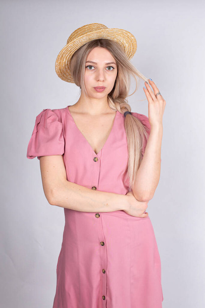 Kobieta z blond włosami i białą skórą na szarości w kapeluszu i różowej sukience - Zdjęcie, obraz