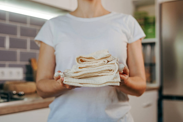 Closeup of young woman holding reusable cotton produce bags. Zero waste and sustainable packaging concept. - 写真・画像