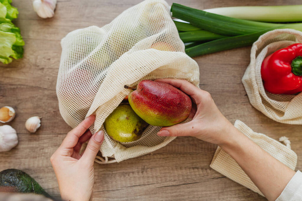Top näkymä nuori nainen tilalla uudelleenkäytettäviä puuvillaa tuottaa pussi päärynöitä. Nollajäte ja kestävä pakkausmalli. - Valokuva, kuva