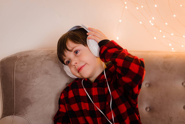 Un ragazzo con le cuffie è sdraiato sul divano stile di vita. Il ragazzo ascolta la musica. L'umore di anno nuovo. - Foto, immagini