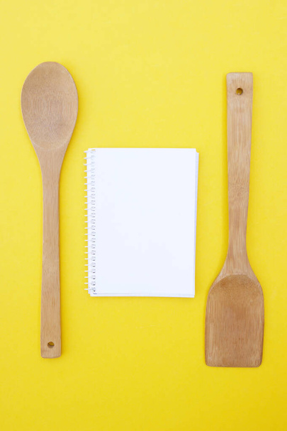 Ein Satz Bambusgeschirr und leeres Notizbuch auf leuchtend gelbem Hintergrund. Kochkonzept. - Foto, Bild