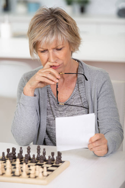 senior woman learns to pay chess - Foto, afbeelding