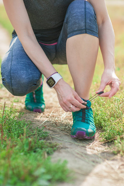 Active woman tying running shoes outdoor. Healthy lifestyle concept - Foto, imagen