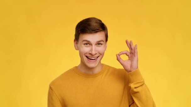 Man Gesturing Okay Sign With Hand Nodding Head, Yellow Background - Materiał filmowy, wideo