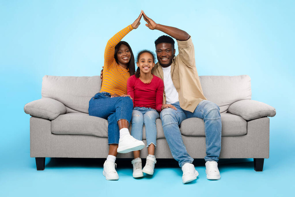 Les parents noirs font un toit symbolique des mains au-dessus de leur enfant - Photo, image