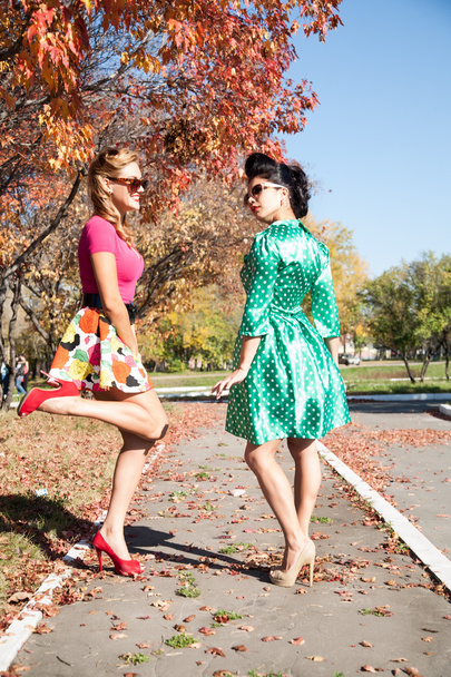 秋の公園で歩いてカラフルなドレスの 2 人の女の子 - 写真・画像