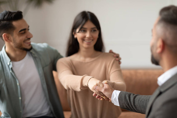 Happy couple shaking hands with therapist at office - Photo, Image