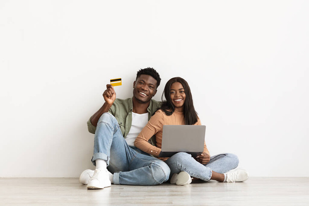 Emotional african american couple using laptop and credit card - Foto, imagen