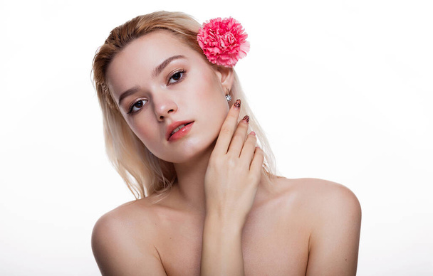 Charmante jeune femme à la fleur rose. Modèle blond tenant fleur rose derrière l'oreille isolé sur fond blanc. Concept de beauté et de soins de santé espace libre pour le texte - Photo, image
