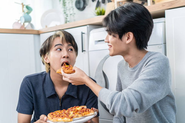 Asiático guapo hombre gay familia sentado en el suelo, comer pizza juntos. Atractiva pareja masculina romántica lgbtq celebrar aniversario, pasar tiempo cenar en la cocina en casa. Concepto homosexual-LGBTQ - Foto, Imagen