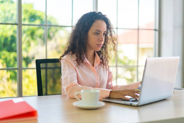 Donna latina che lavora con laptop e carta sullo spazio di lavoro a casa - Foto, immagini