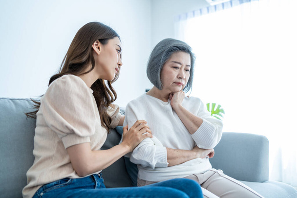 Asian loving daughter comforts upset elderly mother crying for problem. Young caring woman support, consoling and understand empathy to stressed senior older mom in tears at home. Family relationship. - Foto, Imagen