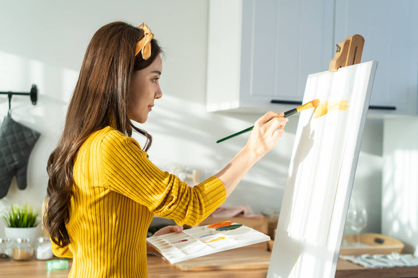 Asian young talented woman artist coloring on painting board in house. Attractive beautiful female draw art picture, creating artwork with watercolor paint and brush enjoy creativity activity at home. - Fotografie, Obrázek