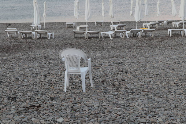 Dawn on the seashore, empty deck chairs, chairs and closed umbrellas on the beach. - Valokuva, kuva