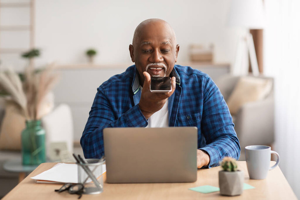 Ανώτερος αφρικανός που χρησιμοποιεί τη φωνητική αναζήτηση στο Smartphone στο γραφείο - Φωτογραφία, εικόνα