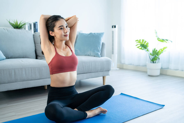 Asian young beautiful active woman doing Yoga Pilates workout at home. Attractive girl in sportswear feel happy and relax, follow exercise instruction video from online trainer in living room in house - Photo, Image