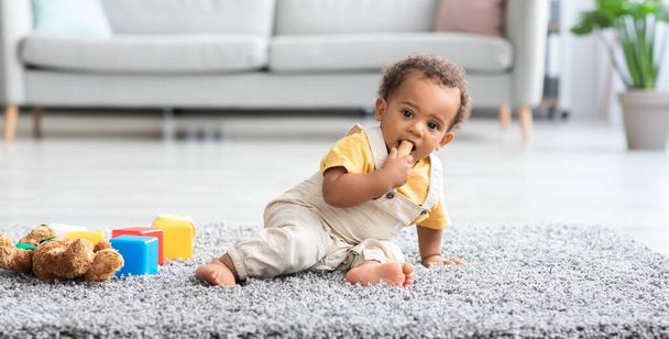 Baby Safety. Adorable Little Black Boy Biting Wine Cork Found On Floor - Фото, изображение