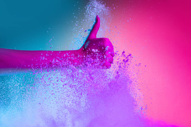 Female hand and explosion of colored, neoned powder on pink blue studio background with copy space. Magazine cover, wallpaper design - Foto, imagen